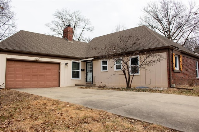 view of front of house with driveway, an attached garage, roof with shingles, and a chimney