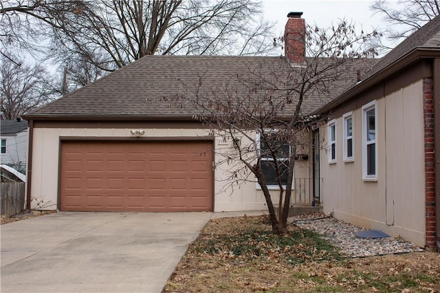 view of front of house with concrete driveway, a garage, a chimney, and a shingled roof