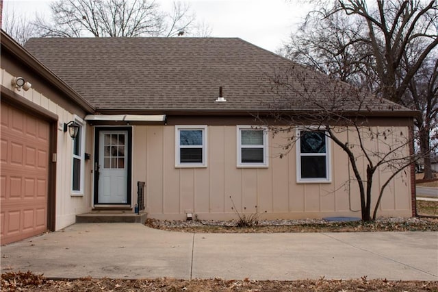 exterior space with a garage, board and batten siding, and roof with shingles