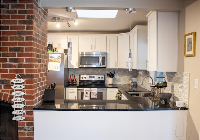 kitchen with a sink, stainless steel appliances, backsplash, and white cabinetry