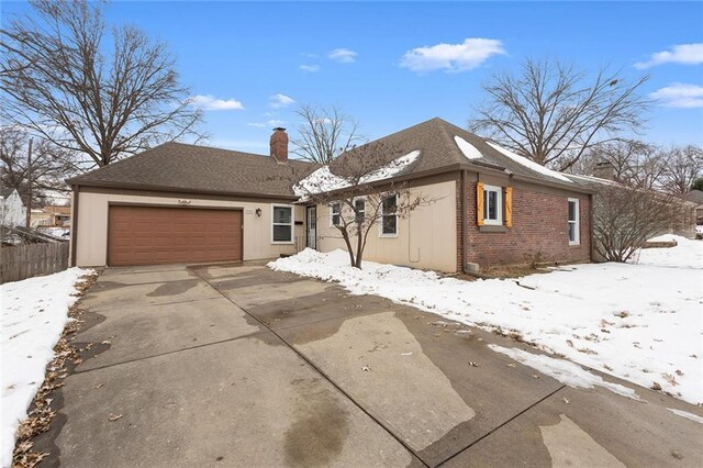 view of front facade with driveway, an attached garage, a shingled roof, a chimney, and brick siding