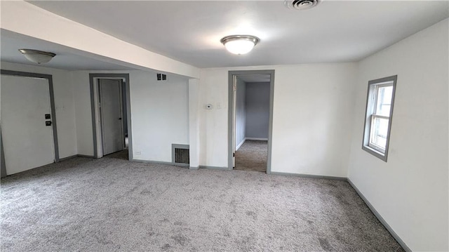 spare room with carpet flooring, baseboards, and visible vents