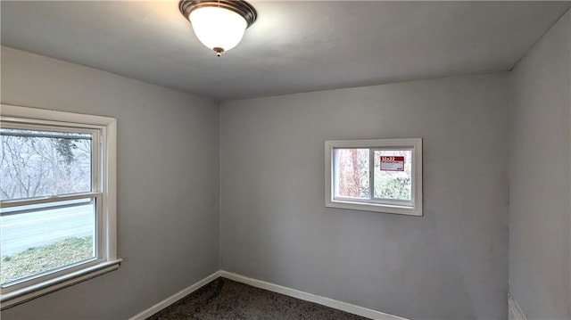 unfurnished room featuring baseboards and dark colored carpet