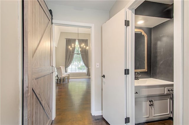 11643 Glen Arbor Ter, Kansas City, MO 64114 - hallway with a barn door, a sink, dark wood finished floors, and a chandelier