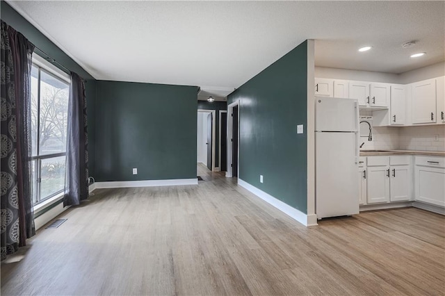 kitchen with white cabinetry, plenty of natural light, light wood-type flooring, and freestanding refrigerator