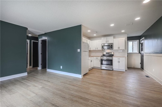 kitchen featuring visible vents, light wood-style flooring, appliances with stainless steel finishes, white cabinets, and light countertops