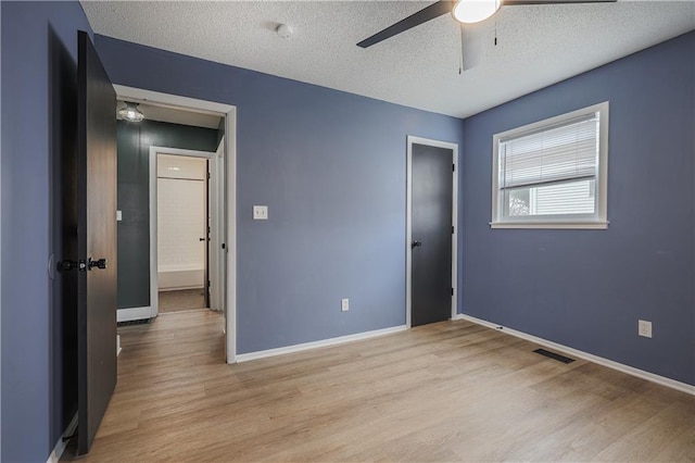 unfurnished bedroom with light wood finished floors, visible vents, ceiling fan, baseboards, and a textured ceiling