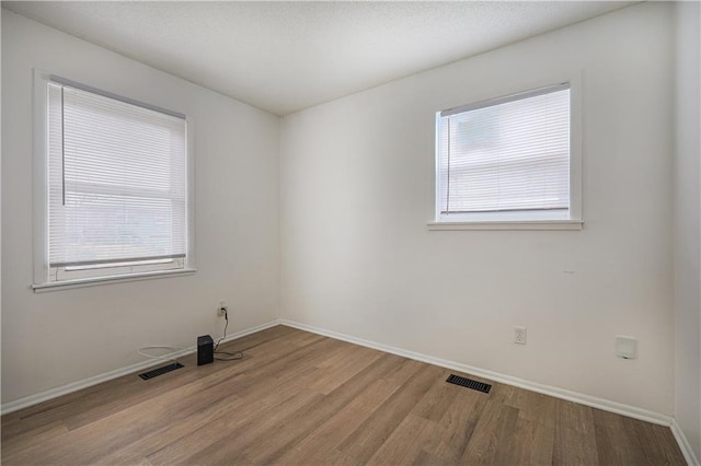 spare room featuring wood finished floors, visible vents, and a wealth of natural light