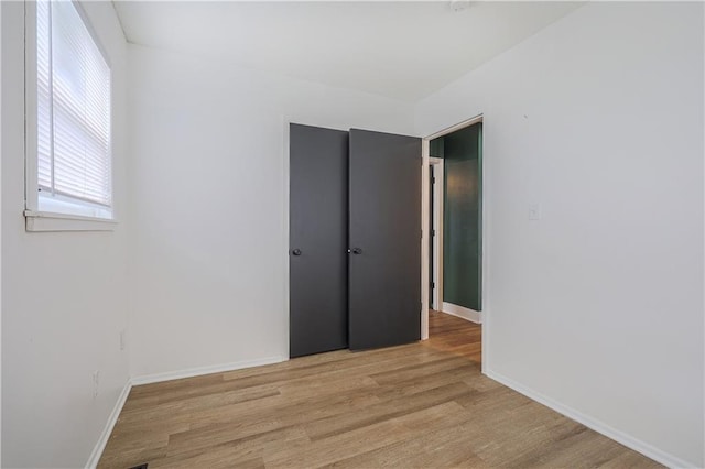 unfurnished room with light wood-type flooring and baseboards