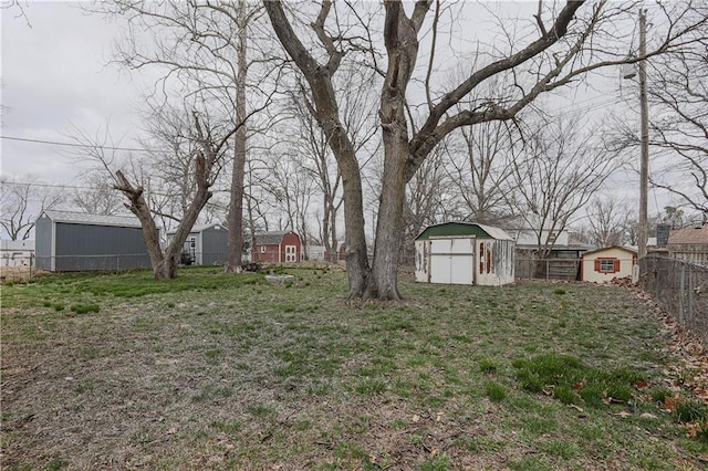 view of yard featuring a storage shed, fence, and an outdoor structure