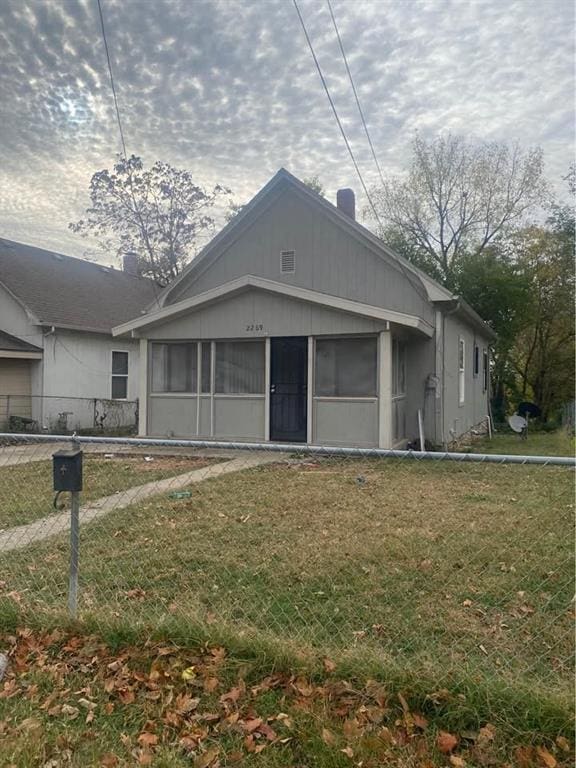 bungalow-style house featuring a front yard, fence, and a sunroom