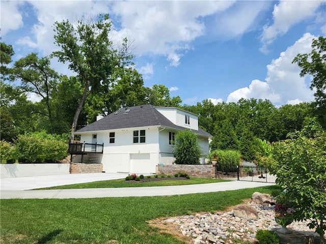view of property exterior featuring stucco siding, a lawn, concrete driveway, and fence