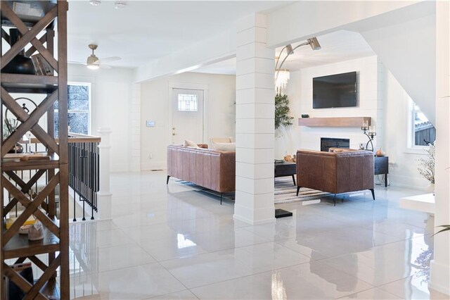 living area featuring marble finish floor, a fireplace, baseboards, and a ceiling fan