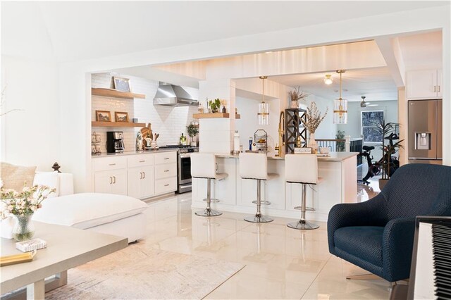 kitchen with tasteful backsplash, wall chimney range hood, a breakfast bar, appliances with stainless steel finishes, and open shelves
