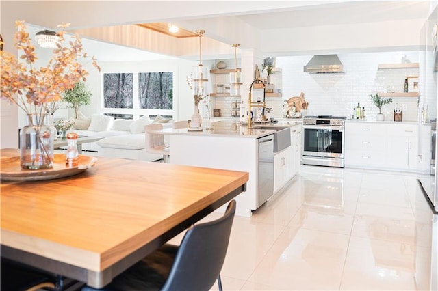 kitchen with wall chimney range hood, white cabinetry, appliances with stainless steel finishes, light countertops, and decorative backsplash