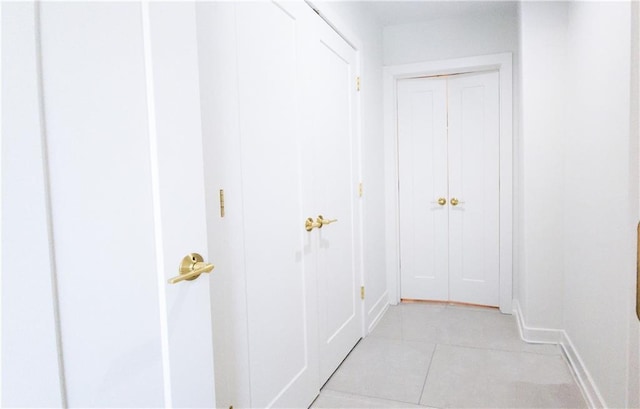 hallway with light tile patterned floors and baseboards