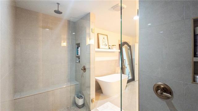 bathroom featuring tile patterned floors, a walk in shower, tile walls, and a freestanding tub