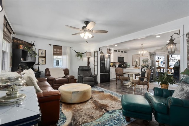 living area with dark wood-style floors, recessed lighting, and ceiling fan with notable chandelier