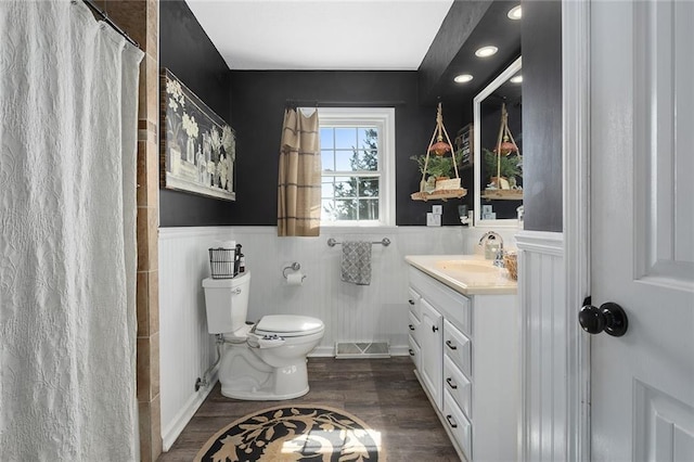 bathroom featuring a wainscoted wall, visible vents, toilet, wood finished floors, and vanity