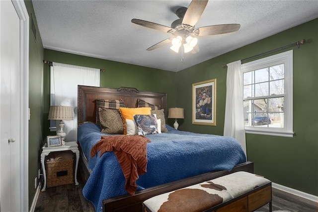 bedroom with a textured ceiling, baseboards, and wood finished floors