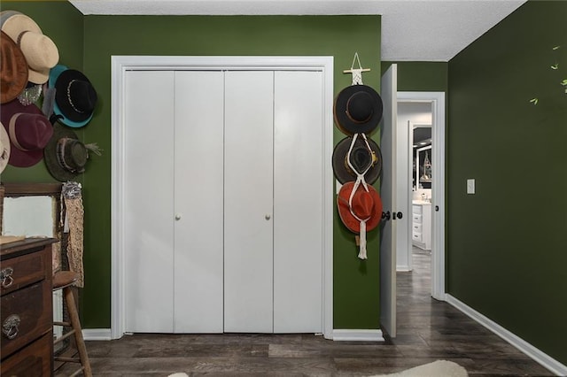 bedroom featuring a closet, a textured ceiling, dark wood-type flooring, and baseboards