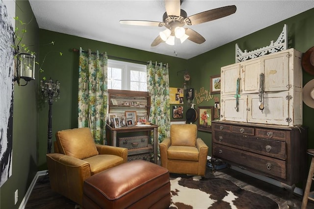 living area with baseboards and ceiling fan