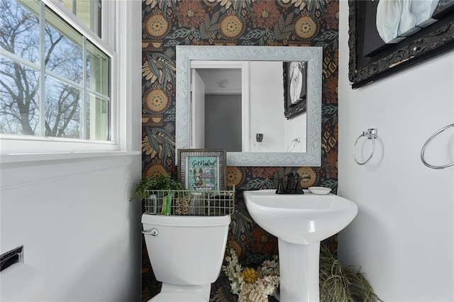 half bath featuring wallpapered walls and toilet