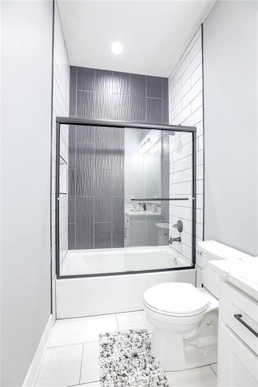 full bathroom with combined bath / shower with glass door, vanity, baseboards, tile patterned flooring, and toilet