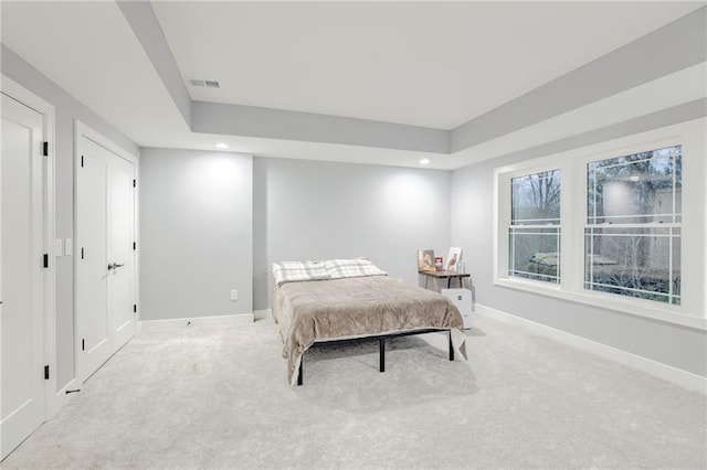 carpeted bedroom with visible vents, baseboards, a raised ceiling, and recessed lighting