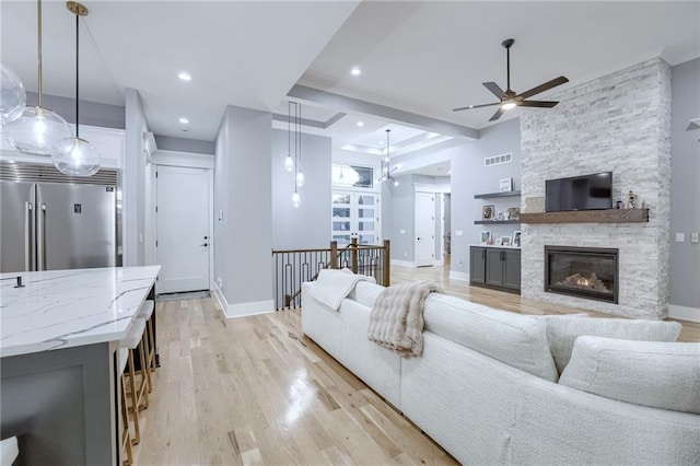 living room featuring light wood-style flooring, ceiling fan, and baseboards