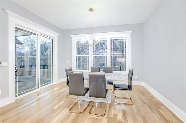 dining area featuring light wood-style flooring, an inviting chandelier, baseboards, and a healthy amount of sunlight