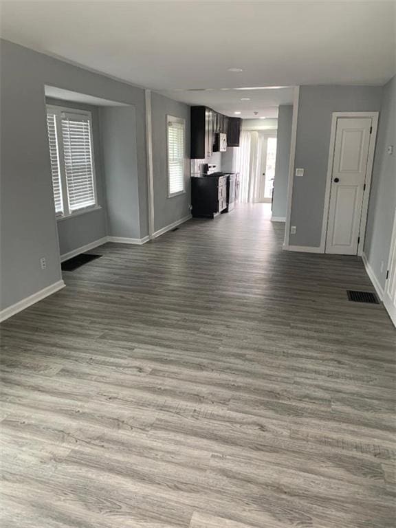 unfurnished living room featuring wood finished floors, visible vents, and baseboards