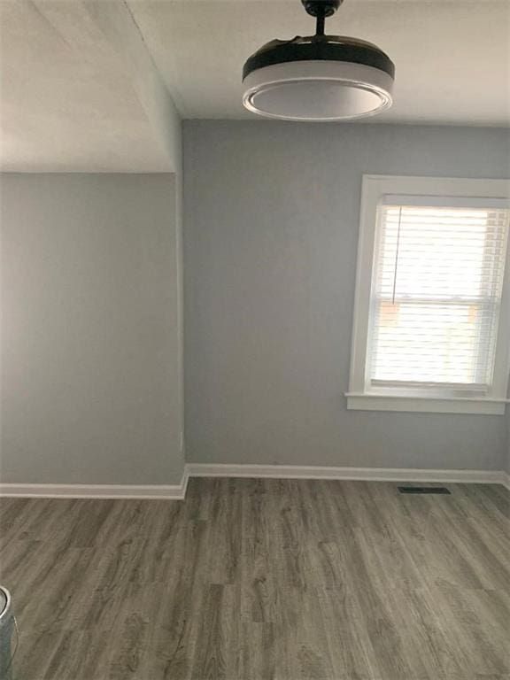 spare room featuring visible vents, baseboards, and wood finished floors