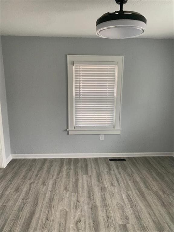 empty room with visible vents, baseboards, and wood finished floors