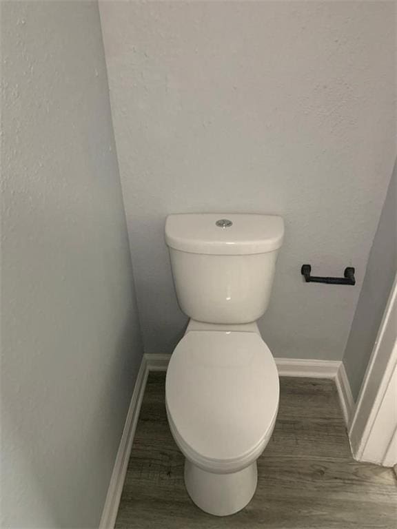 bathroom featuring baseboards, toilet, and wood finished floors