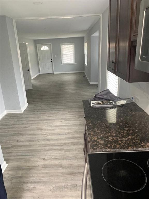 kitchen featuring baseboards, open floor plan, dark stone counters, light wood-type flooring, and electric range