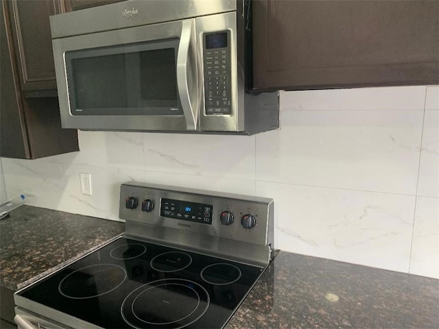 kitchen with stainless steel appliances, dark brown cabinets, decorative backsplash, and dark stone counters