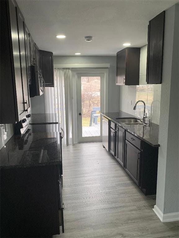 kitchen featuring a sink, dark countertops, light wood-style floors, baseboards, and dishwasher