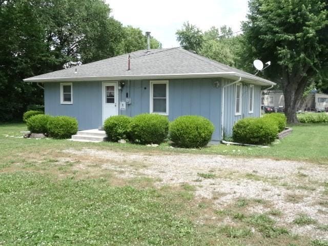 view of front facade with a front yard and roof with shingles