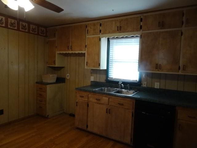 kitchen with dark countertops, ceiling fan, dishwasher, wood finished floors, and a sink