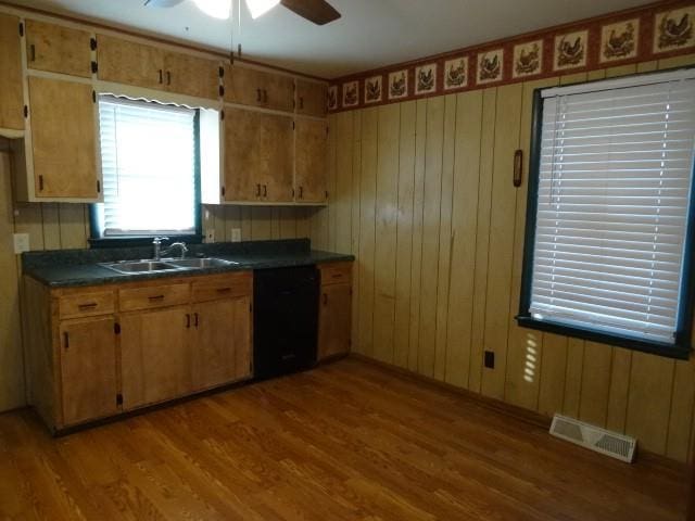 kitchen featuring visible vents, a sink, dark countertops, wood finished floors, and dishwasher