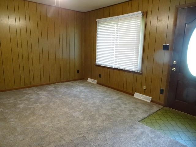 foyer with visible vents, wood walls, and carpet floors