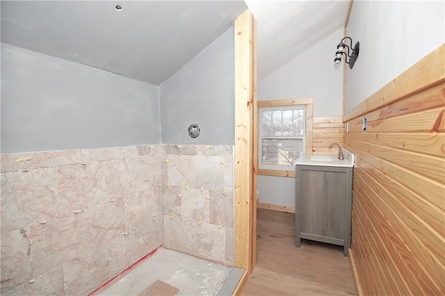 bathroom with wood finished floors, vanity, a wainscoted wall, toilet, and lofted ceiling