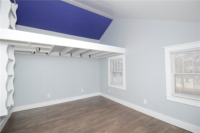 spare room with baseboards, lofted ceiling, and wood finished floors