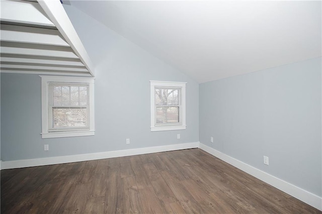 interior space with baseboards, vaulted ceiling with beams, and dark wood-style flooring