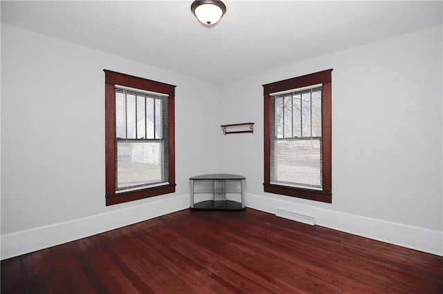 spare room with baseboards, wood finished floors, and visible vents