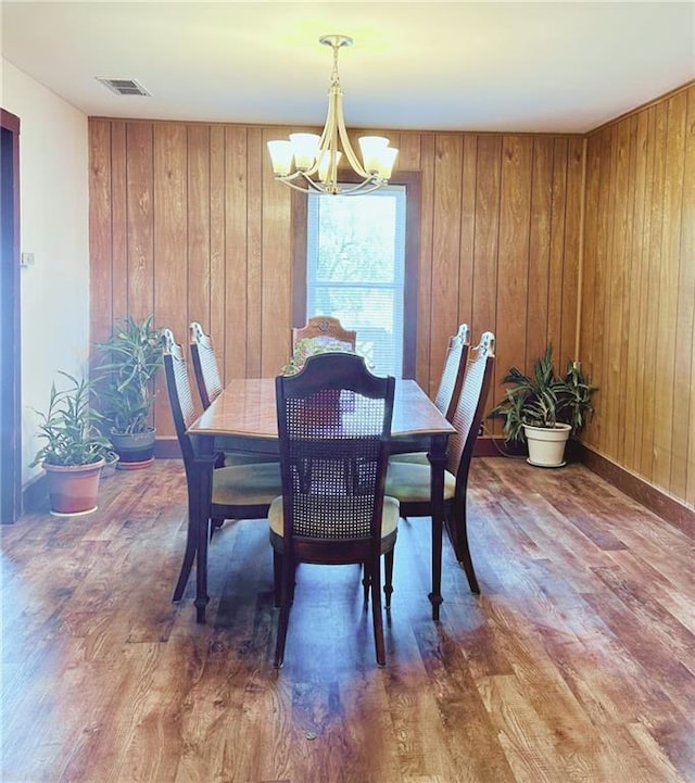 4900 E 219th St, Peculiar, MO 64078 - dining space with a chandelier, wood finished floors, and wooden walls