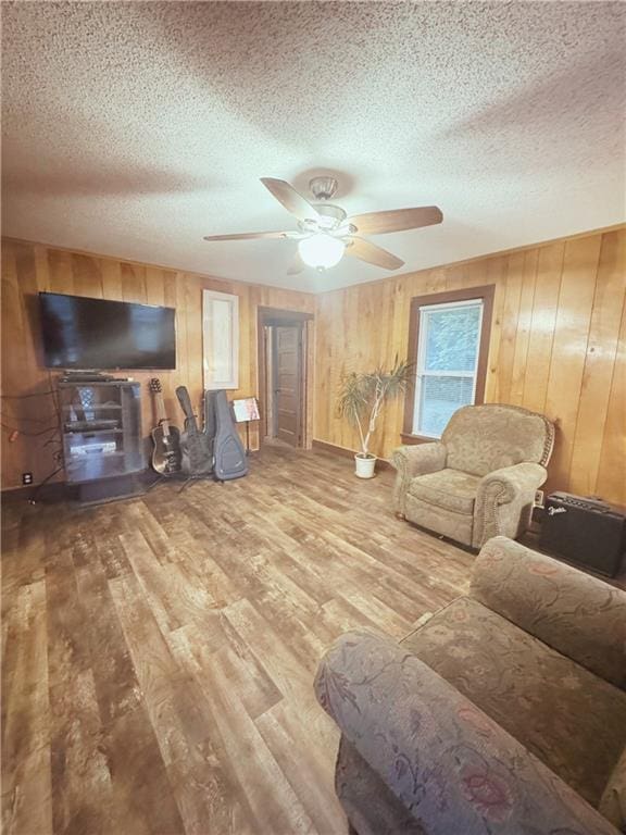 4900 E 219th St, Peculiar, MO 64078 - living area featuring a textured ceiling, wooden walls, wood finished floors, and ceiling fan