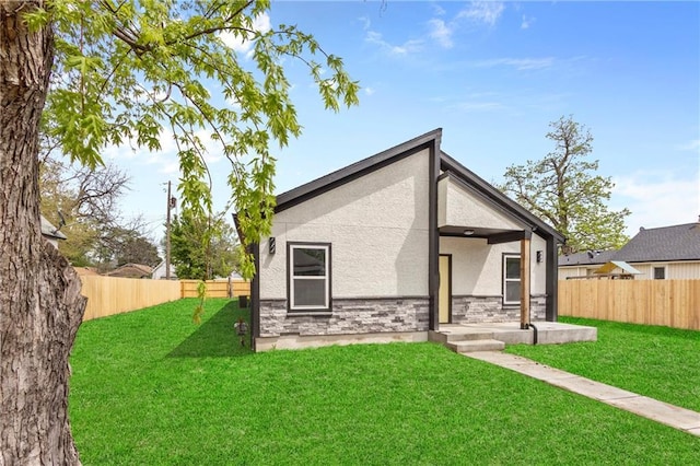 1219 S 36th St, Kansas City, KS 66106 - rear view of property featuring a lawn, stone siding, stucco siding, and a fenced backyard