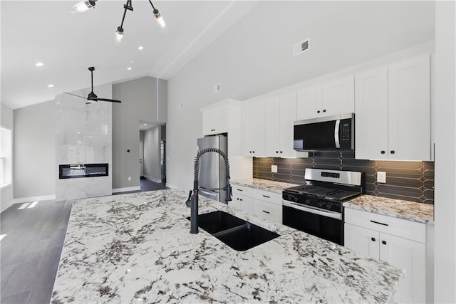 1219 S 36th St, Kansas City, KS 66106 - kitchen with a sink, stainless steel appliances, white cabinets, visible vents, and tasteful backsplash